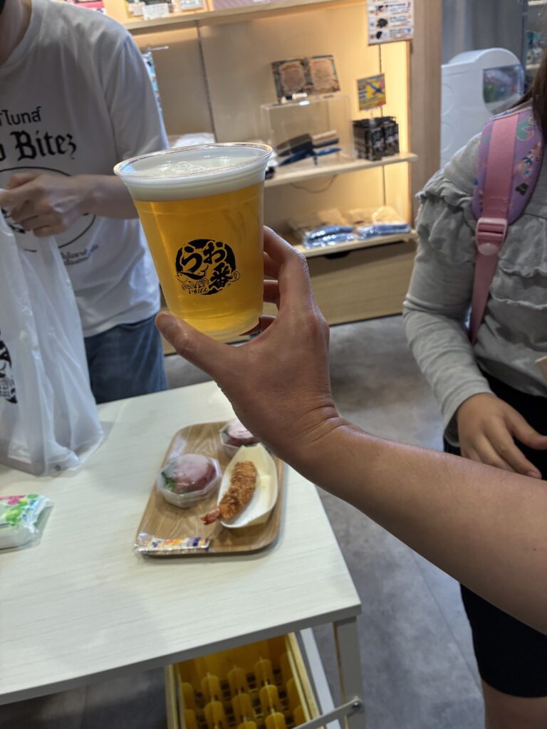 うお一番の開店待ち時間に飲食スペースで楽しむ、エビフライとビールの写真。